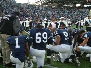 Penn State football players
kneel in prayer before a game