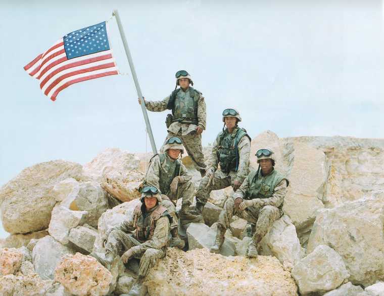 Planting a flag on a rock pile in Iraq